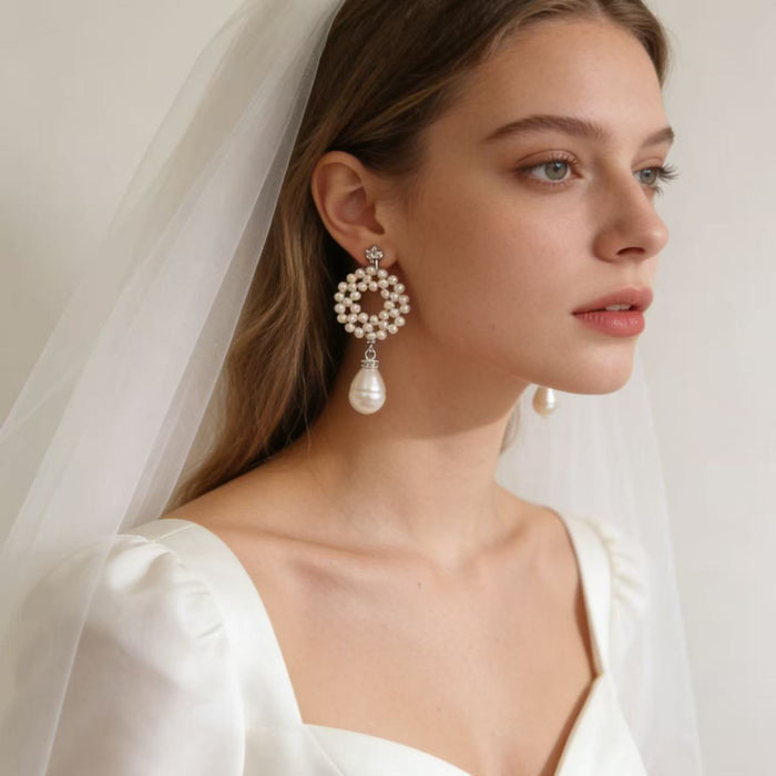 Elegant bridal statement earrings handcrafted with genuine freshwater pearls in a woven circular design and baroque pearl drop.