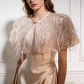 Handmade nude bridal capelet featuring illusion tulle, shimmering sequins, and soft feather embellishments.
