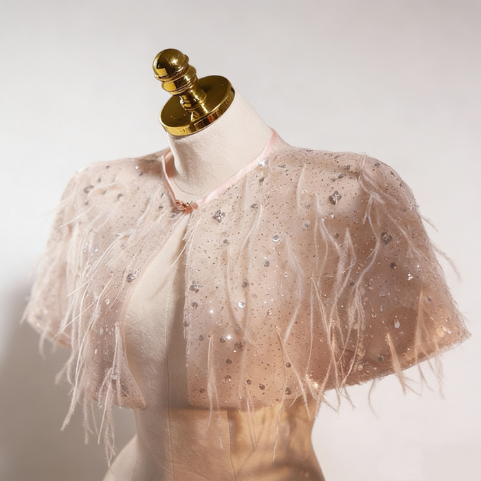Handmade nude bridal capelet featuring illusion tulle, shimmering sequins, and soft feather embellishments.