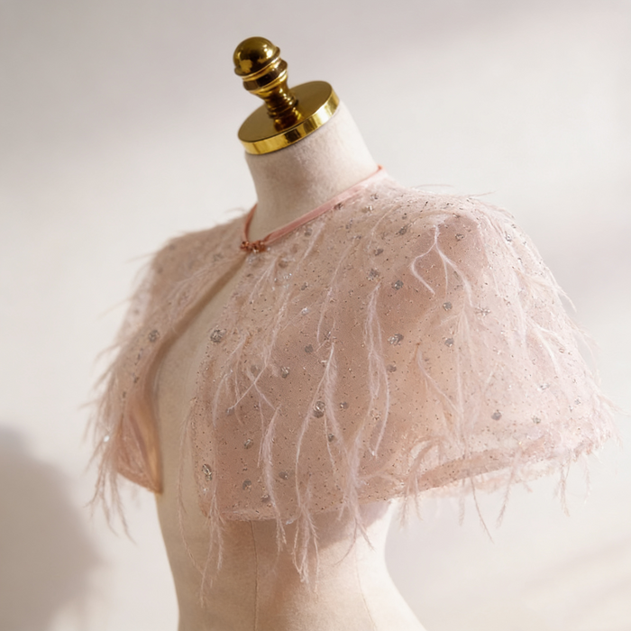 Handmade nude bridal capelet featuring illusion tulle, shimmering sequins, and soft feather embellishments.