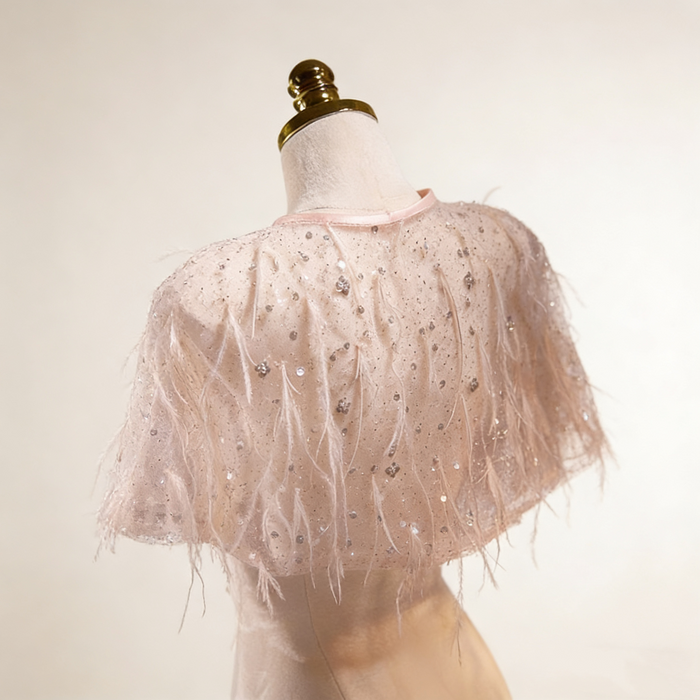 Handmade nude bridal capelet featuring illusion tulle, shimmering sequins, and soft feather embellishments.