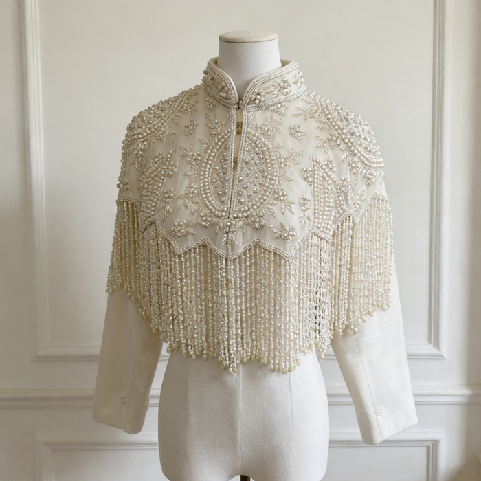 Handmade illusion tulle bridal cape embroidered with faux pearls, floral beadwork, and elegant pearl fringe.