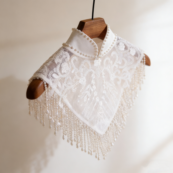 Handmade bridal cape featuring illusion tulle, pearl bead embroidery, shimmering sequins, and elegant pearl fringe.