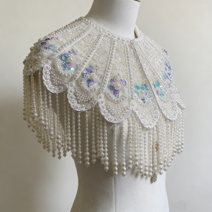 Handmade bridal cape featuring hand-sewn sequin bead embroidery, iridescent floral details, and cascading faux pearl fringe.