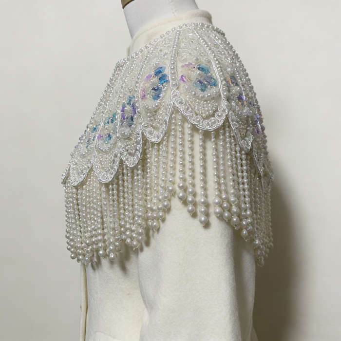 Handmade bridal cape featuring hand-sewn sequin bead embroidery, iridescent floral details, and cascading faux pearl fringe.