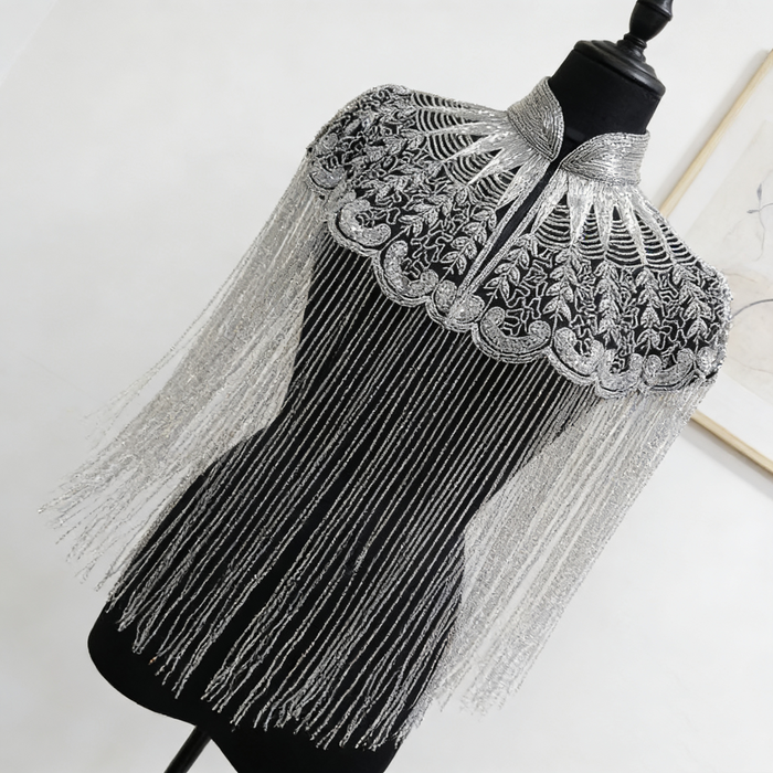 Handmade silver bridal cape featuring intricate bead embroidery, shimmering sequins, seed beads, and flowing metallic fringe.