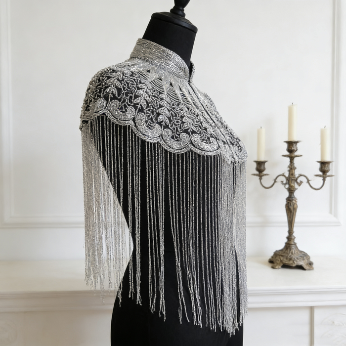 Handmade silver bridal cape featuring intricate bead embroidery, shimmering sequins, seed beads, and flowing metallic fringe.