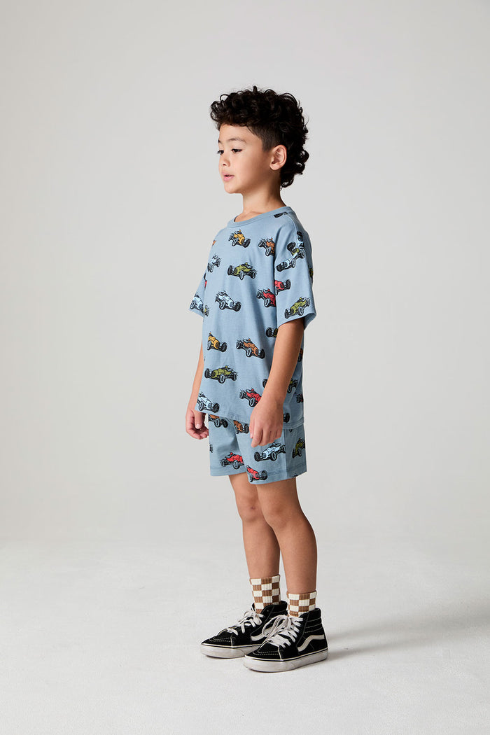 Full body side angle view of a boy wearing the Chaser Have a Nice Smile Tee on a neutral background