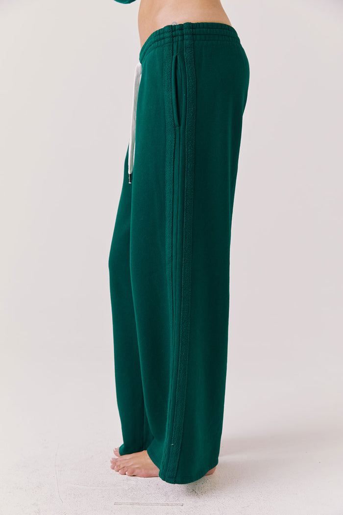 Side view of woman wearing Chaser’s Hazel Joggers in Blue Grass Green on a white background