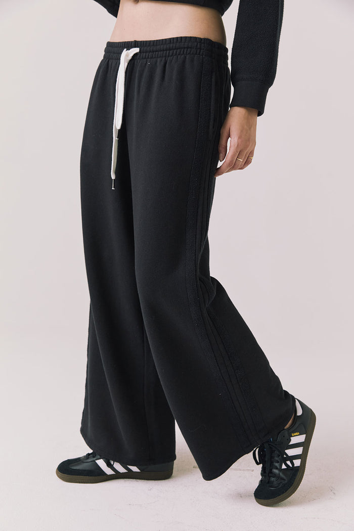 Side view of woman wearing Chaser’s Hazel Joggers in true black on a white background