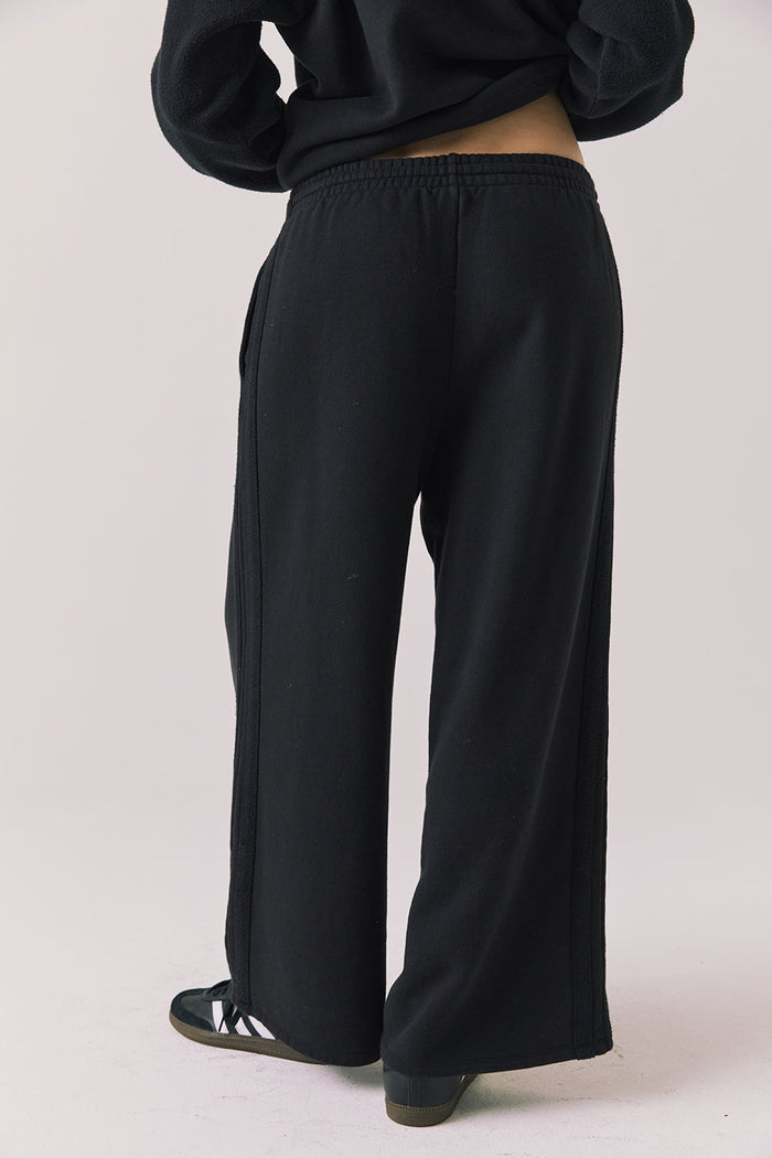 Back view of woman wearing Chaser’s Hazel Joggers in true black on a white background