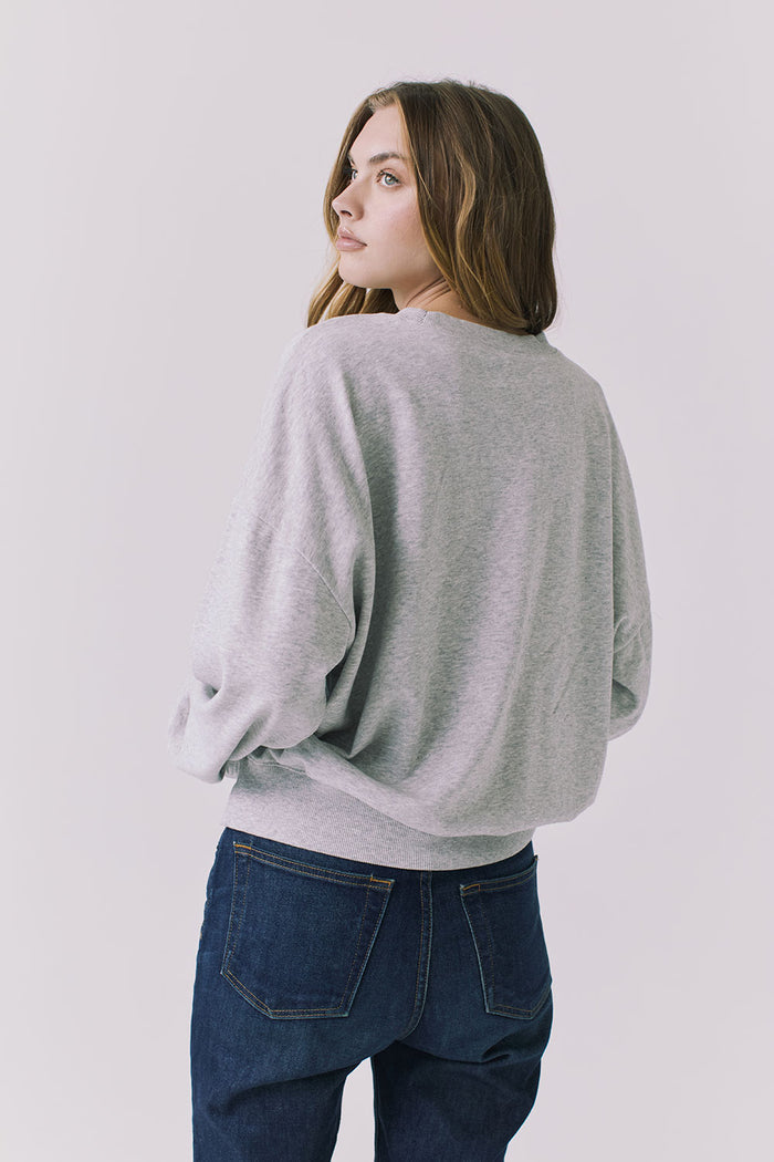 Back view of a woman wearing Chaser's gray Health Is Wealth Long Sleeve on a plain background