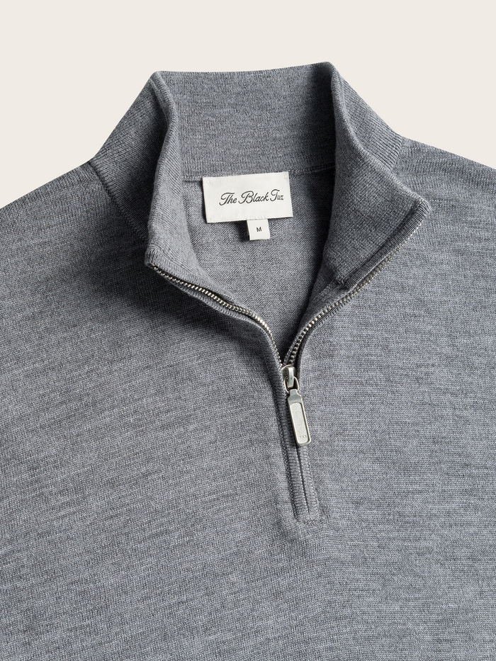 Close-up of heather grey quarter-zip sweater collar and zipper pull