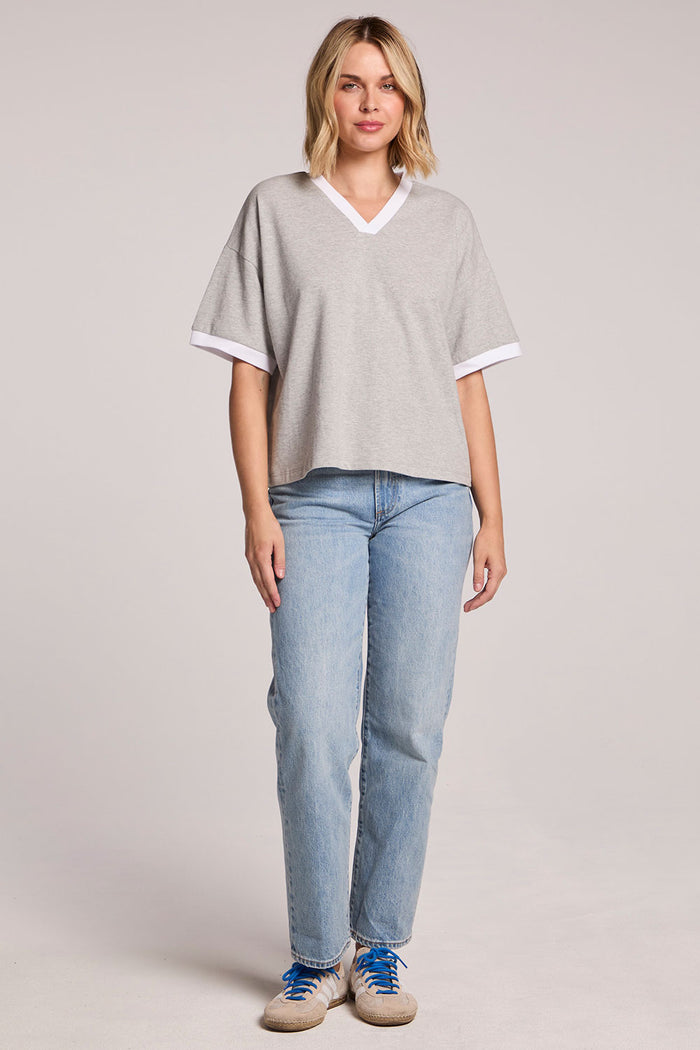 A full body view of a woman wearing the Chaser Heather Grey Eden Tee and sneakers on a neutral background