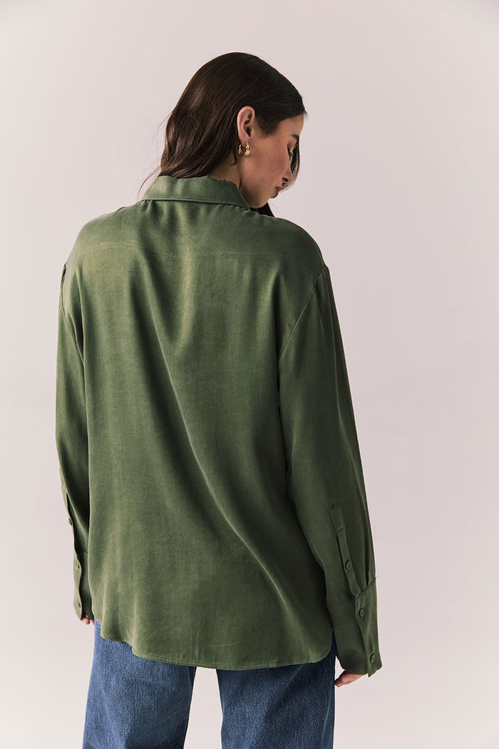 Back view of a model wearing the Helenaa button-down shirt in bronze green with collared neckline and relaxed silhouette,  against a plain background.
