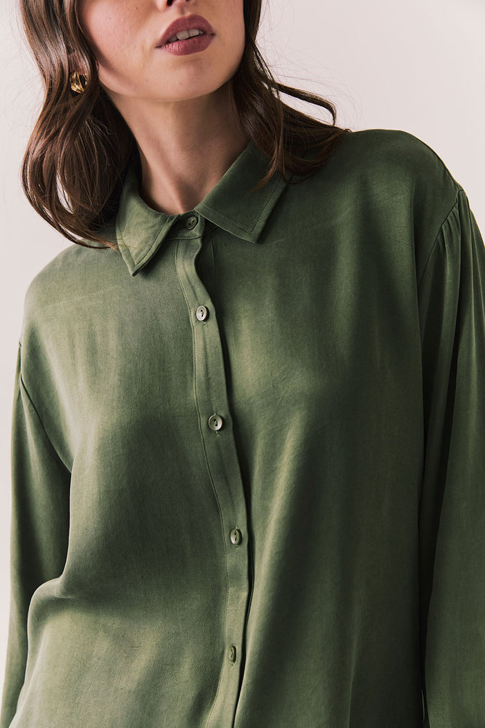 Front view of a model wearing the Helenaa button-down shirt in bronze green with collared neckline and relaxed silhouette,  against a plain background.