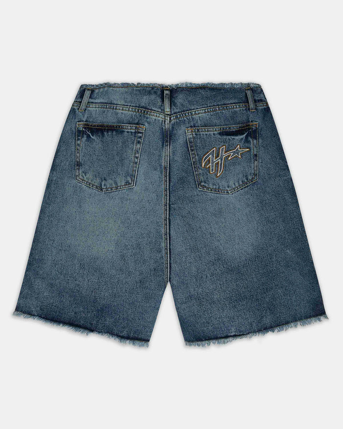 Back view of blue denim shorts with a raw frayed hem, featuring a gold embroidered logo on the right pocket.