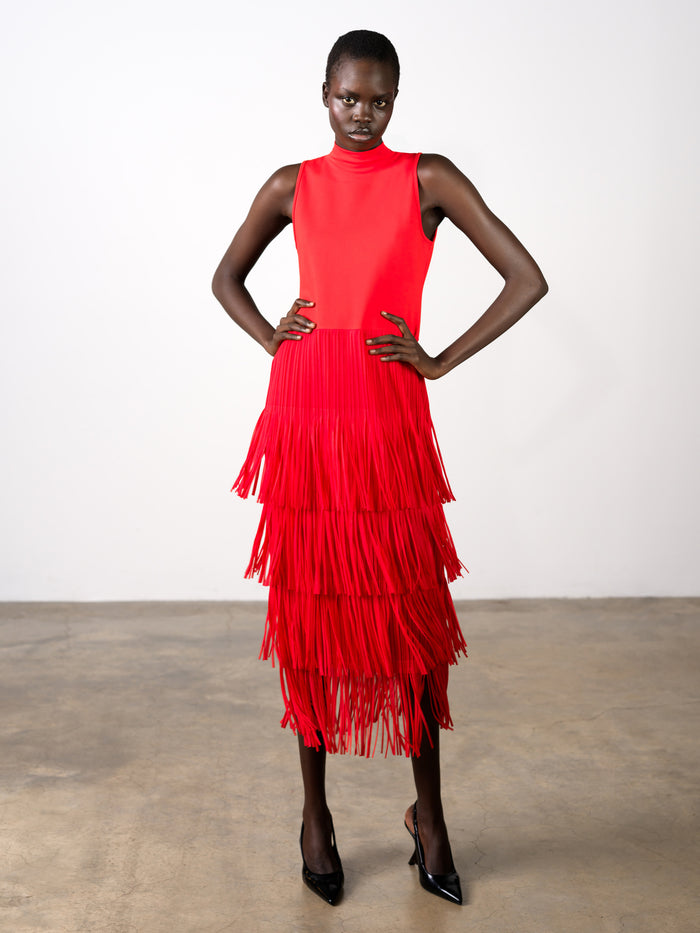 A woman wearing a sleeveless high neck midi dress with a fringe layered skirt.