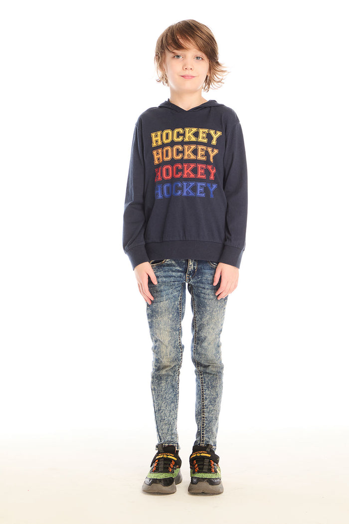 Full body view of boy wearing Chaser’s Hockey navy blue pullover hoodie with ‘Hockey’ text and distressed jeans on a white background