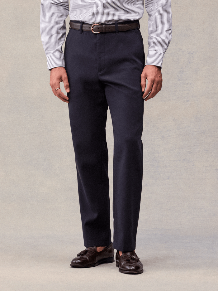 Admiral navy suit pants worn with a brown belt and tassel loafers, cropped waist-to-shoe view.