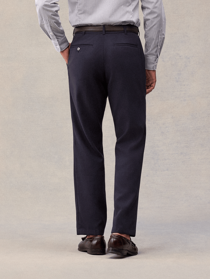 Admiral navy suit pants from behind, buttoned welt back pockets, cropped waist-to-shoe view.