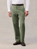 Dusty sage suit pants with a brown belt and black penny loafers, cropped waist-to-shoe view.