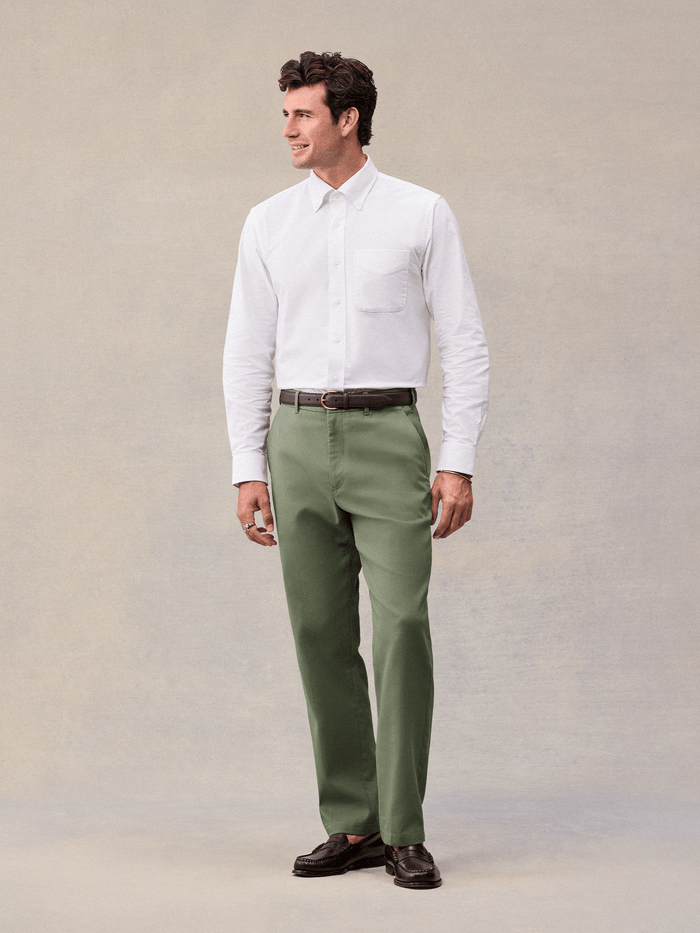 A man in dusty sage suit pants and a white oxford shirt, full length front view.