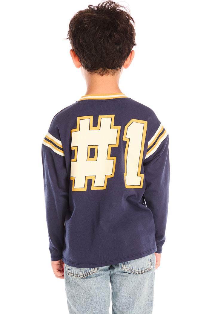 Back view of boy wearing Chaser’s I Am #1 navy long sleeve top with large bold “#1” printed on the back against a white background