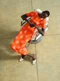 Woman wearing a knitted midi skirt in an orange and cream floral print, with a back centred slit and an elasticated waistband