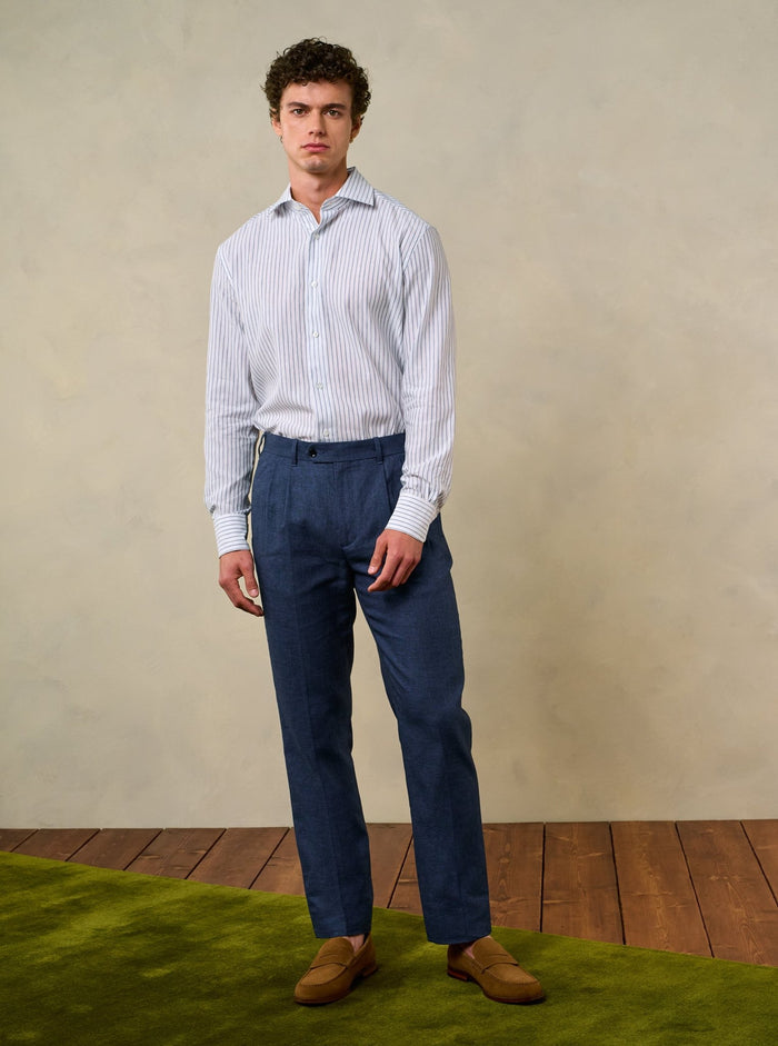 Man in striped shirt and ink blue pleated linen trousers with tan suede loafers