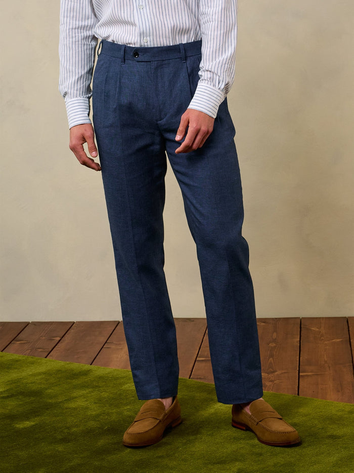 Cropped front view of ink blue pleated linen trousers with tan suede loafers