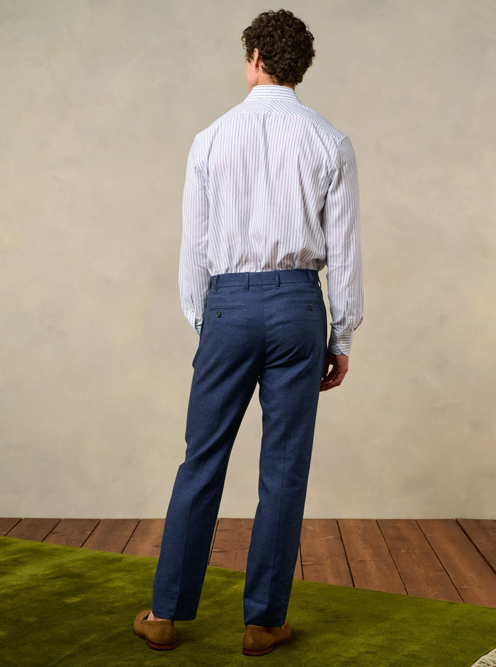 Back view of man in ink blue pleated linen trousers with tan suede loafers