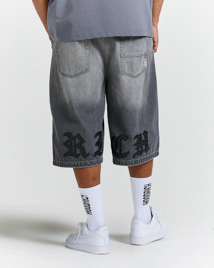 Person wearing gray shorts with 'RICH' branding on a white background