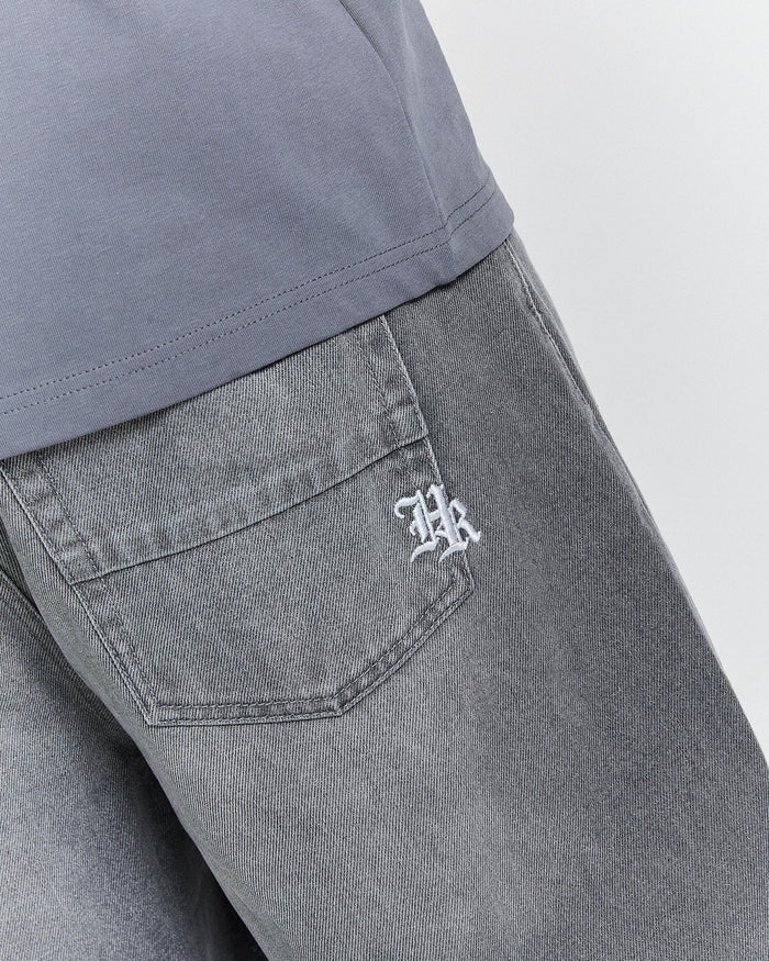 Gray pants with a logo on the pocket against a light gray background