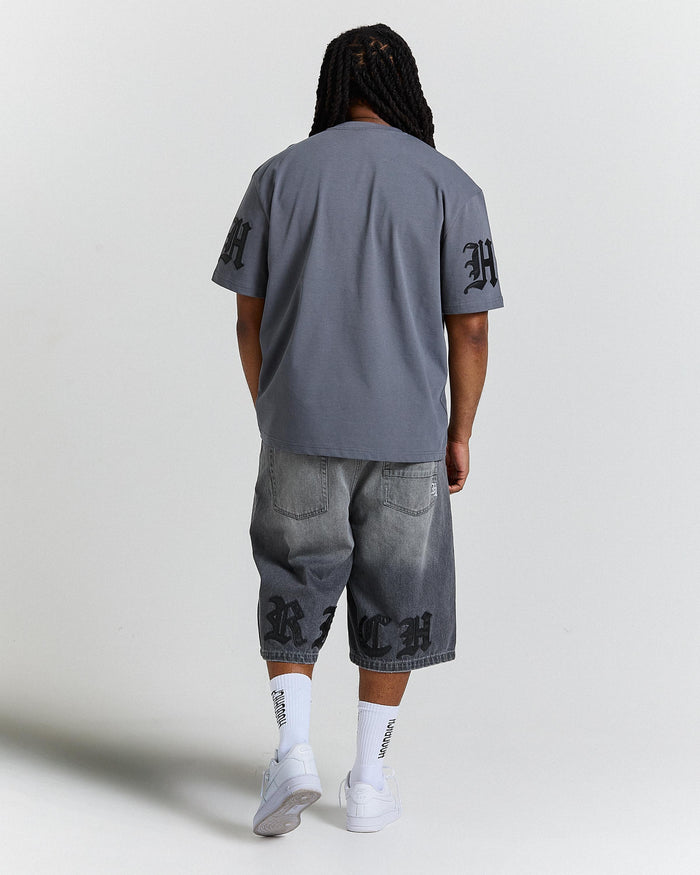 Person wearing a gray t-shirt and baggy shorts with brand logos on a light gray background