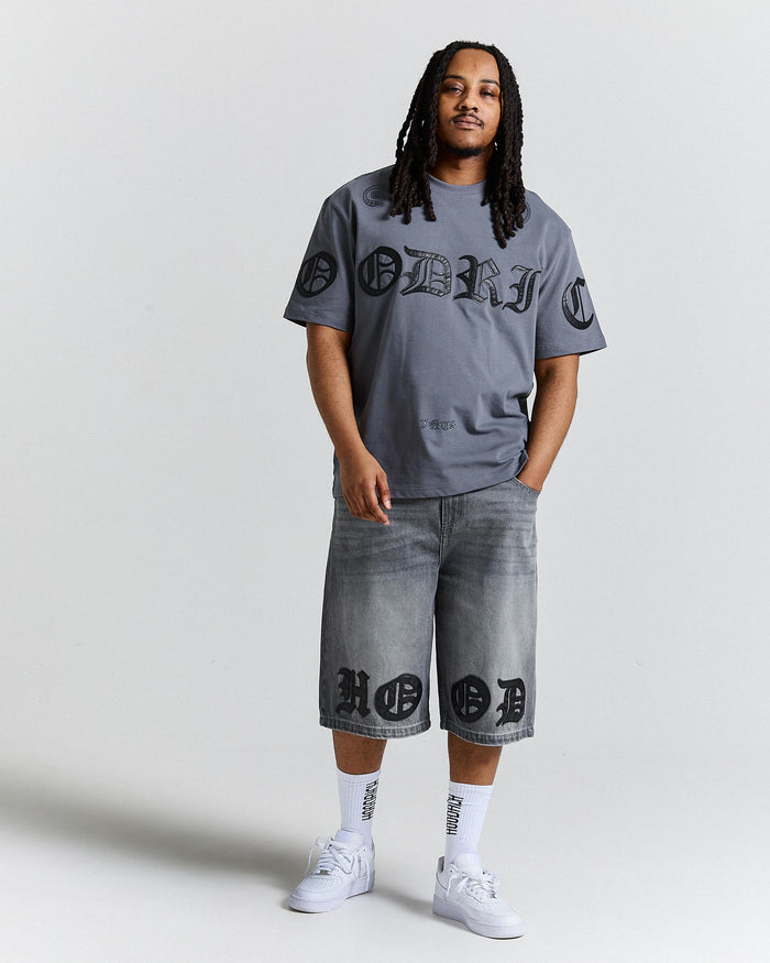 Person wearing a gray t-shirt and shorts with branding, standing against a plain background
