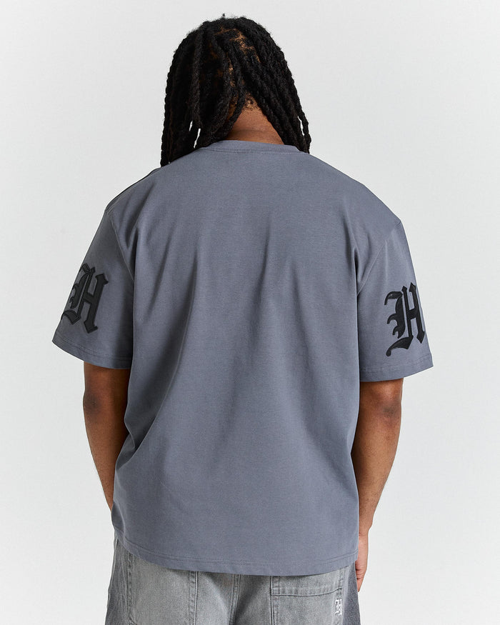 Person wearing a gray t-shirt with black text on sleeves against a white background