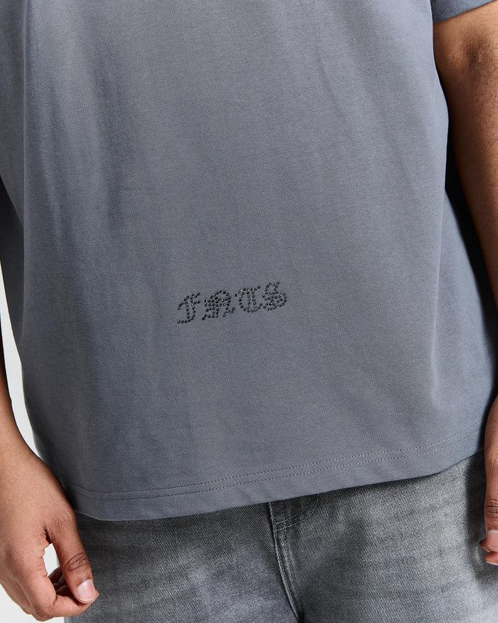 Gray t-shirt with a logo on the chest worn by a person.