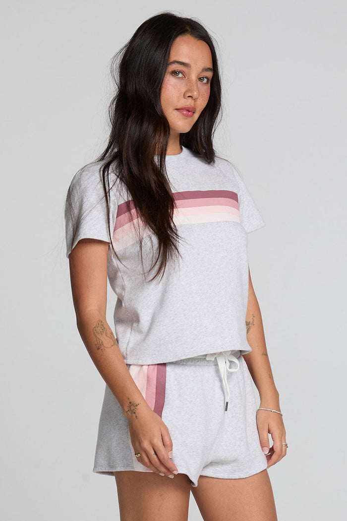 Side view of a woman wearing the Chaser  Isla Light Heather Grey Tee and shorts on a neutral background