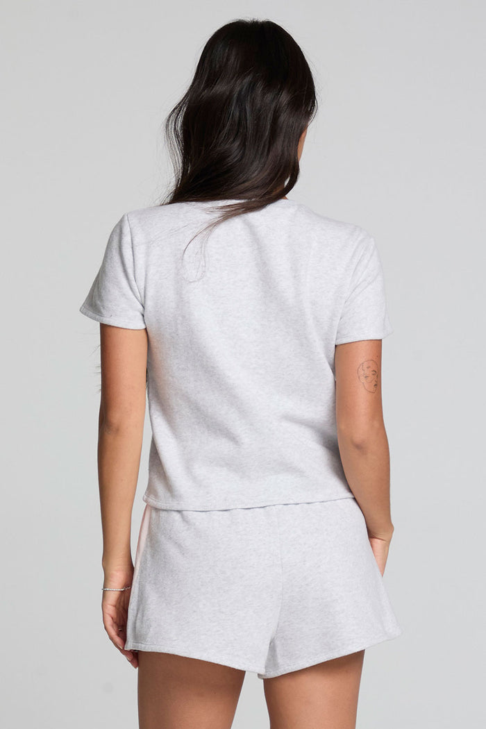 Back view of a woman wearing the Chaser  Isla Light Heather Grey Tee and matching shorts on a neutral background