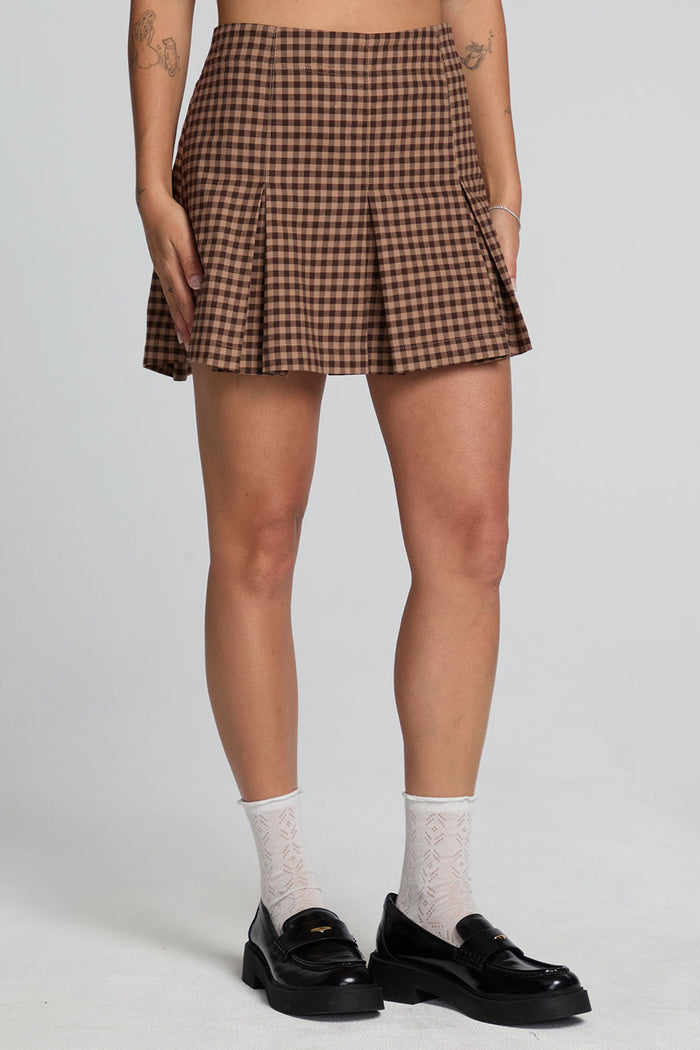 Front view of a woman wearing the Chaser Ivy Choco Check Skort on a neutral background with shoes