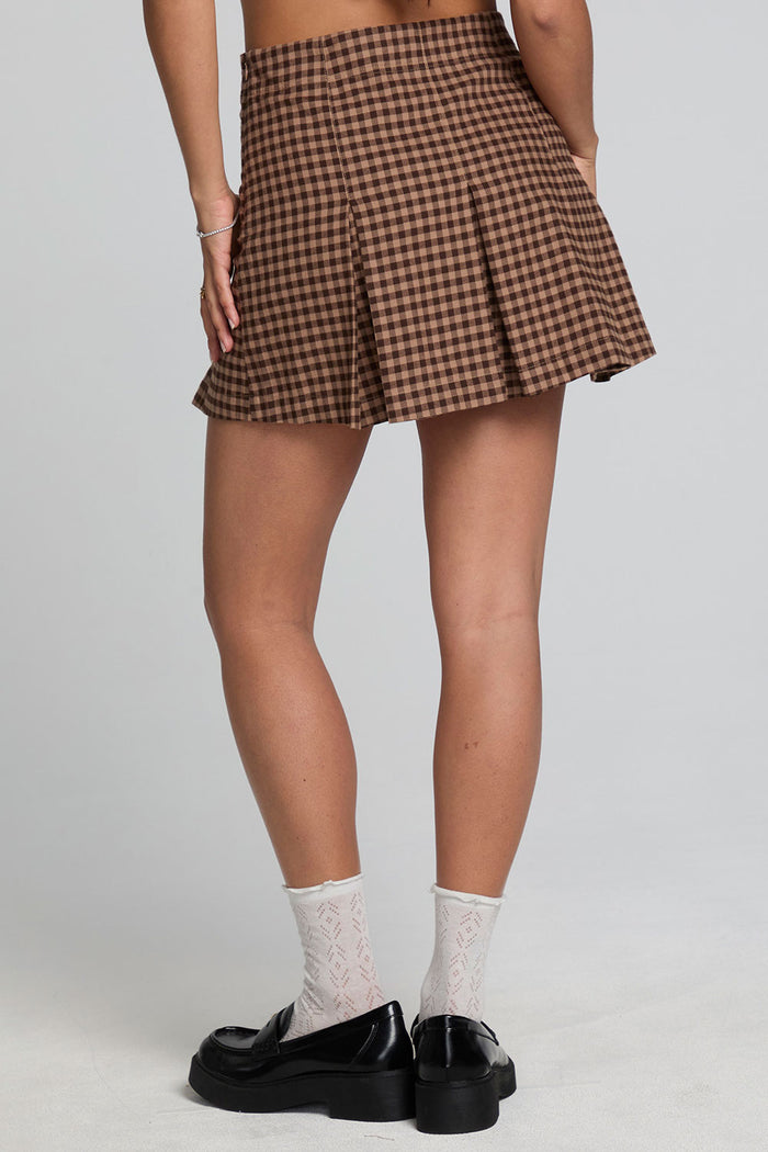 Back view of a woman wearing the Chaser Ivy Choco Check Skort on a neutral background with black loafer shoes