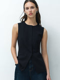 A woman wearing a black tailored long line waistcoat with front pockets, a round neckline and concealed popper fastening.