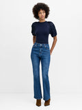 A woman wearing full length high waisted blue jeans with a fly zip and bootcut fit.