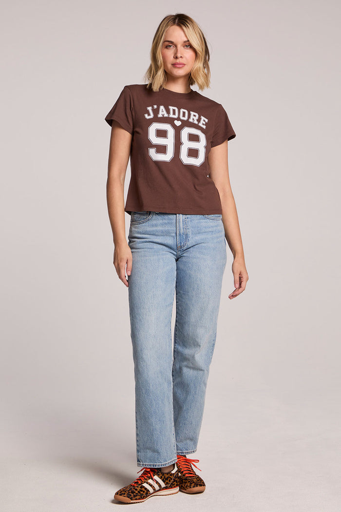 Front view of a woman wearing the Chaser   J'adore 98 Tee and sneakers on a neutral background