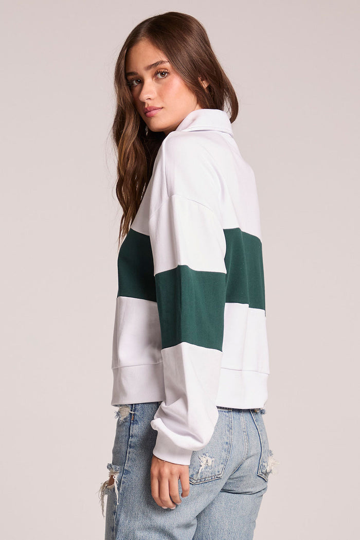 A side view of a woman wearing the Chaser Jaime Pine and White Half Zip on a neutral background