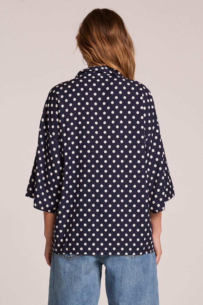 Back view of a woman wearing the Chaser  Jemma Navy Spot Button Down on a neutral background