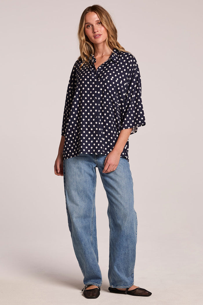 Front view of a woman wearing the Chaser Jemma Navy Spot Button Down and sneakers on a neutral background