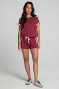Full body front view of a woman wearing the Chaser  Jezz Burnt Red Shorts on a neutral background with arms lowered at sides
