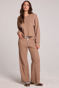 Full body front view of a woman wearing the Chaser Jorgia Camel Pants on a neutral background with matching top